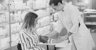 Ein Apothekerin misst den Blutdruck einer Person